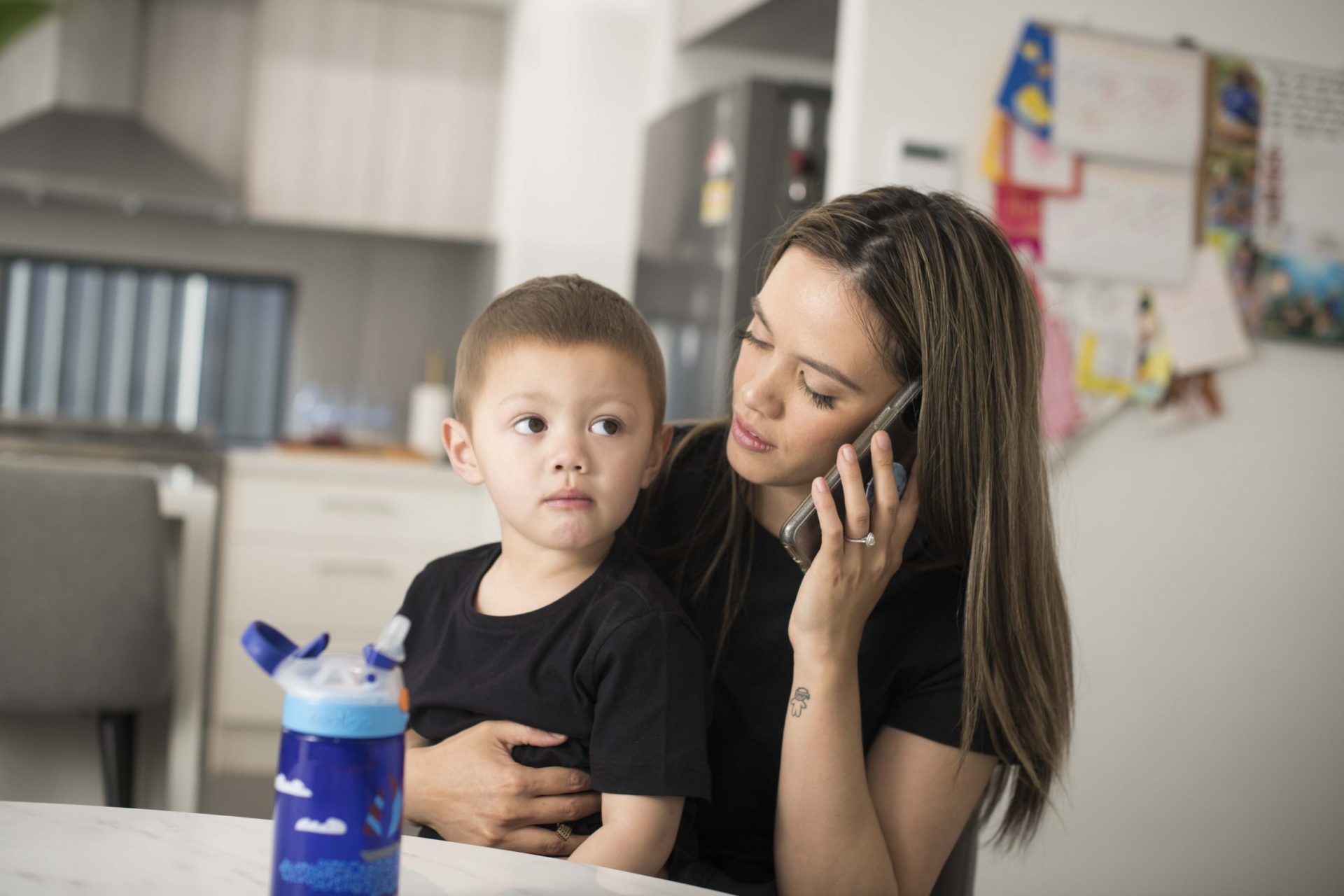 Mother receiving phone call while son sits on her lap