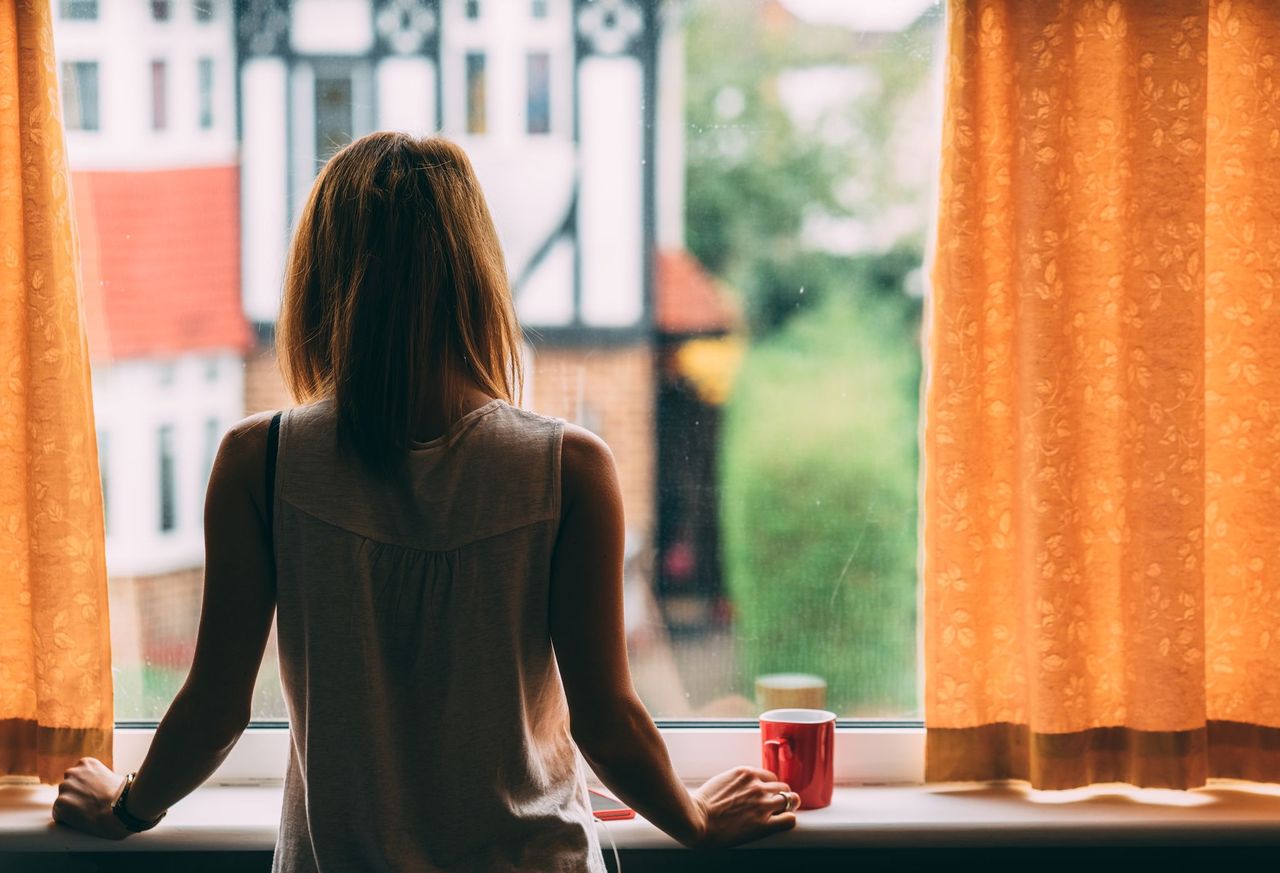 Mother looking out her window feeling isolated