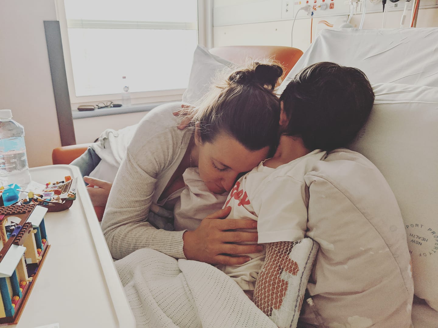 Child with cancer being hugged by her mother