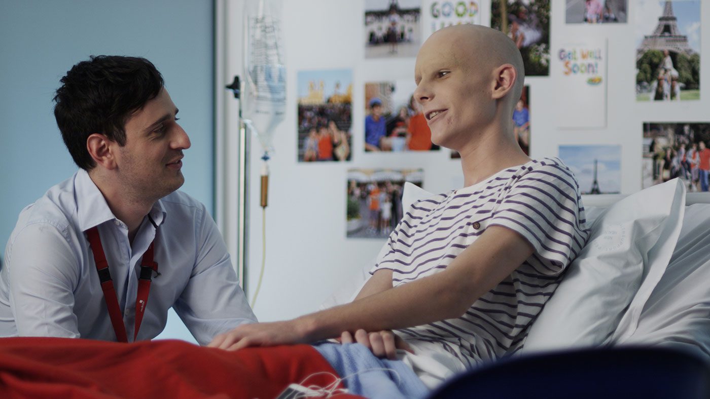 Health worker talking to a young person with cancer in a hospital room