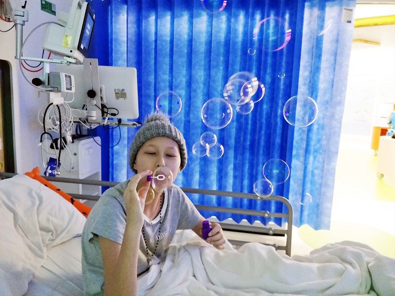 Teenager Teah is blowing bubbles from her hospital bed while having treatment for cancer.