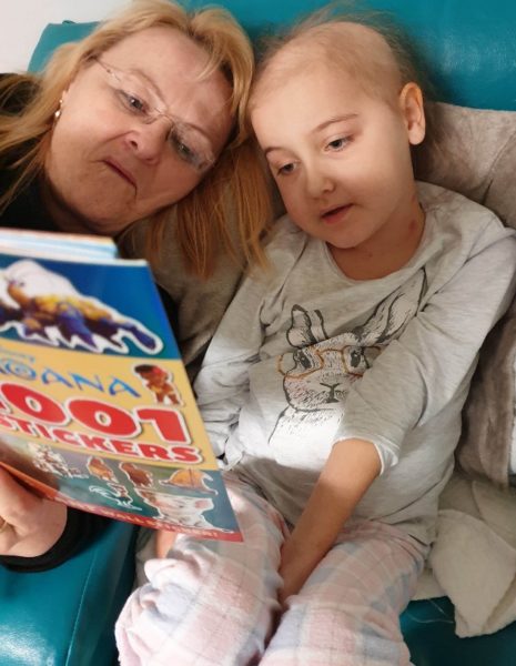 Mum reading to daughter who is sick in hospital bed